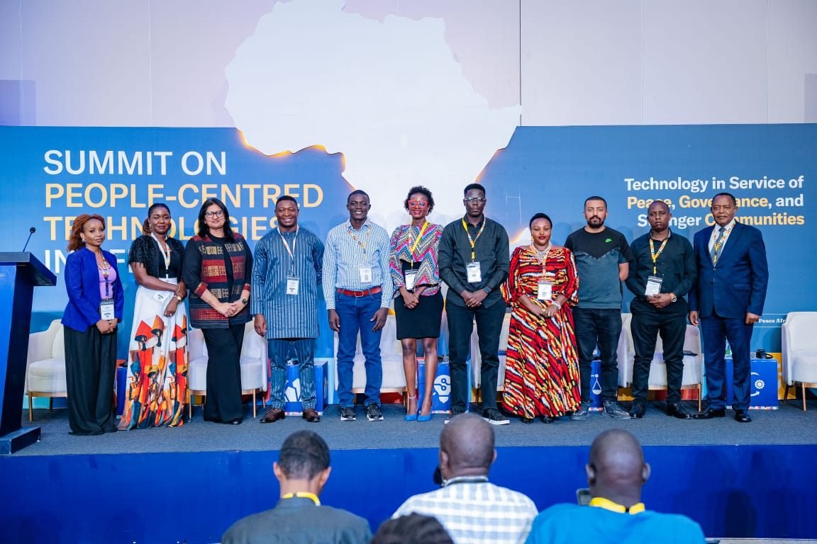 Speakers standing together on stage at the Summit on People-Centred Technologies in Africa, in front of a backdrop with a map of Africa